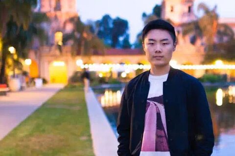 Outdoor portrait of Yuxuan Richard Xie in a jacket and shirt in front of water on the UIUC campus.