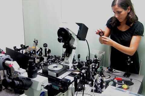Photo of Markita Landry as a graduate student at UIUC looking through a table full of lenses