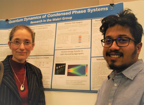 Prof. Nancy Makri and graduate student Sohang Kundu stand next to a poster summarizing their research. 