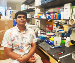 Nathan Kumar sitting in a lab next to his equipment.