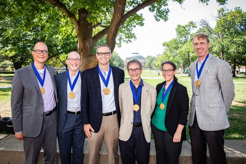 Six members of the SHIELD team stand side by side with on the UIUC quad with medals after the Presidential Medal ceremony in 2021.