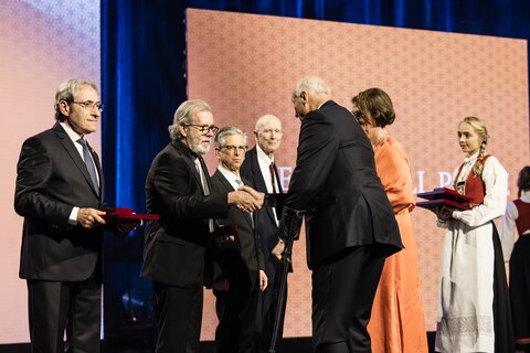 Ralph Nuzzo and other Kavli Prize laureates stand on stage at the Norwegian King Harald shakes their hands.