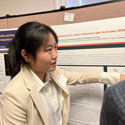 Zhuoran Zhong stands in front of her research poster as she explains her research.