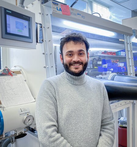 Sagnik Chakrabarti stands in a chemistry lab with equipment in the background