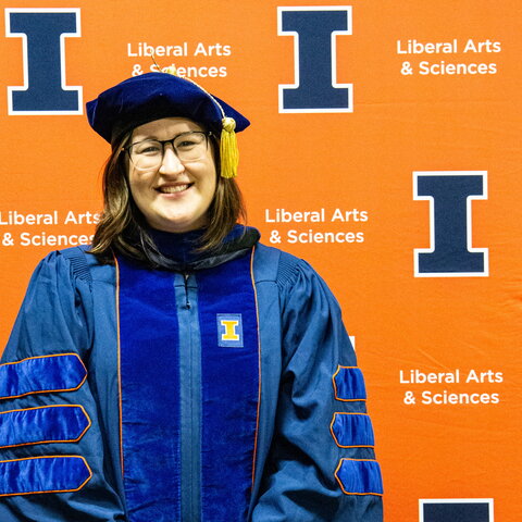 Amanda EAst in a cap and gown in front of an orange background