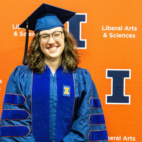 Sophie McClain in a cap and gown in front of an orange background