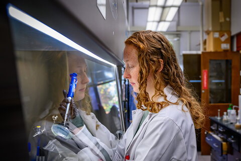 A graduate student in a white lab coat working in the lab 