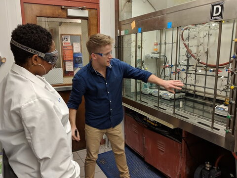 YCC member explains chemistry research to a visitor in a chemistry lab.