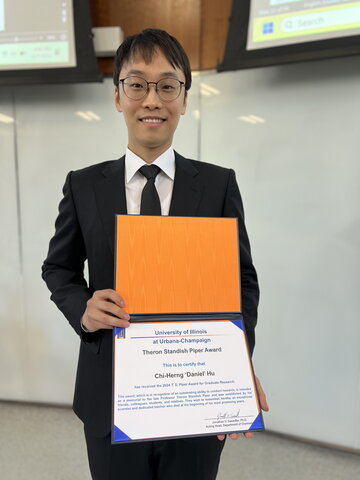 Daniel Hu stands holding a certificate in Chem Annex lecture hall