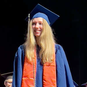 Student in graduation cap and gown on a dark background