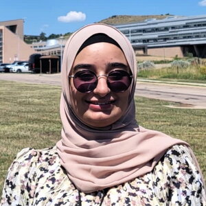 Head shot of Sarah Hasan standing outdoors in front of a building.