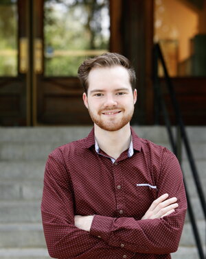 Ethan Walker standing with arms crossed in front of Noyes entrance