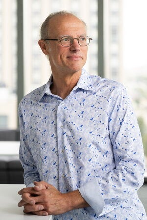 Portrait of Mark Grinstaff with hands folded leaning on table
