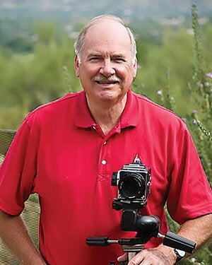 John P. Schaefer standing outdoors with a camera 