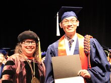 Cathy Murphy stands next to Andrew Feng on stage during convocation.