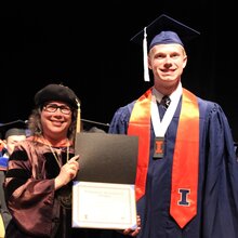 Cathy Murphy stands next to Conrad Milton on stage during convocation.