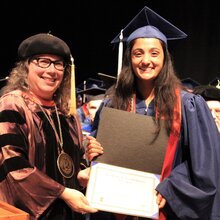 Cathy Murphy stands next to Maya Chattoraj on stage during convocation.