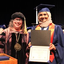 Cathy Murphy stands next to Nawal on stage during convocation.