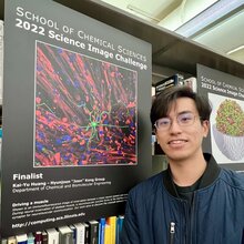 Kai-Yu Huang stands next to a poster of his science image in the Chemistry library