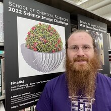 Zane Thornburg stands next to a poster of his science image in the chemistry library