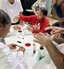 Middle school students sit at a table working on STEM activities