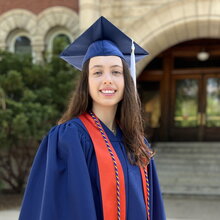 Portrait of Morgan Kennebeck in graduation regalia with Noyes entrance in the background
