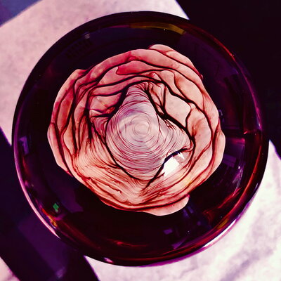 A rose colored and rose shaped pattern as if looking down on the top of a rose