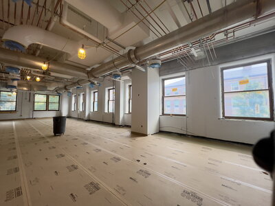 Large, open vacant space that is prepped for the next stage of construction and features more than half a dozen large exterior windows.