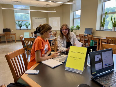 Two people sitting at a table discussing chemistry