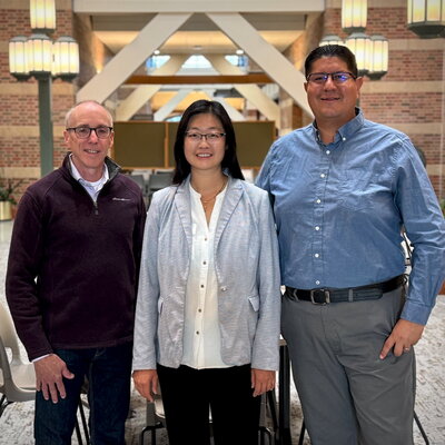 Three people standing side by side in the Beckman atrium