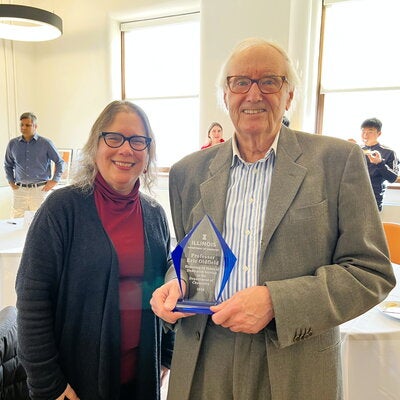 Two people standing together and one is holding a commemorative statue