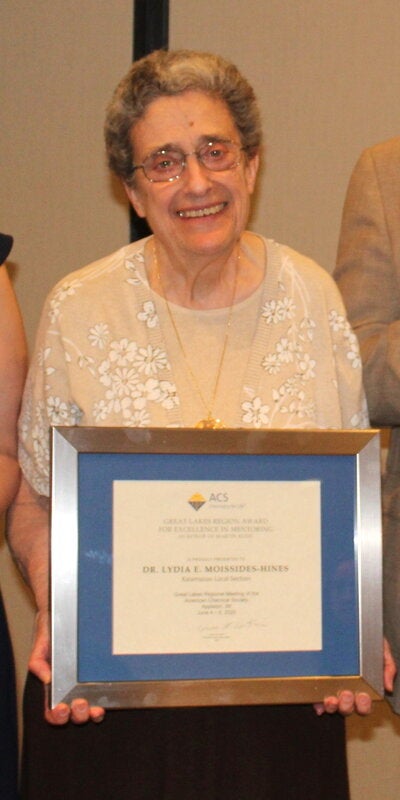 Person standing and holding a framed award