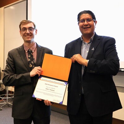 Joaquin Rodriguez Lopez and Seth Putnam stand together holding the Klemperer Award