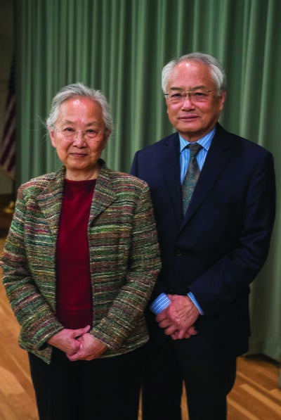 May Lee and Ving Lee standing side by in front of a curtain