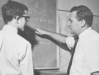 Black and white image of Rudy Marcus and a student in front of a chalk board