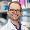 Portrait of Dan Heller in white lab coat in a lab setting