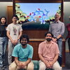 Seven researchers pose around a screen showing an illustration of a molecular structure 