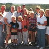 Dr. Milligan and 13 of his family members stand in a group in a location at Yellowstone overlooking a wooded area.