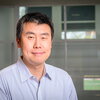 Portrait of Xing Wang sitting in front of a glass background with windows