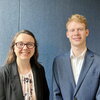 Photo of two people standing next to each other in front of a blue background