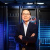 Huimin Zhao standing with arms crossed in front of a large bank of computer data equipment