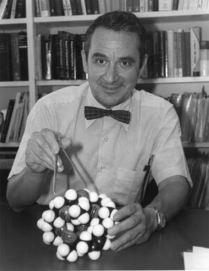E.J. Corey pictured at his desk holding molecule model
