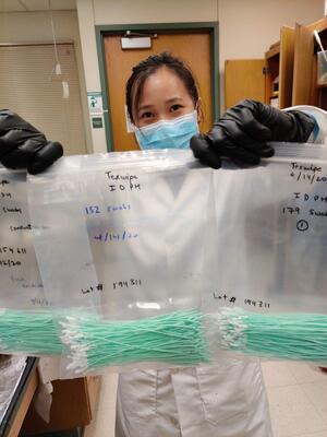 Jia En Aw, a Beckman Institute graduate research assistant and aerospace engineering student, holds 500 swabs being sent for testing