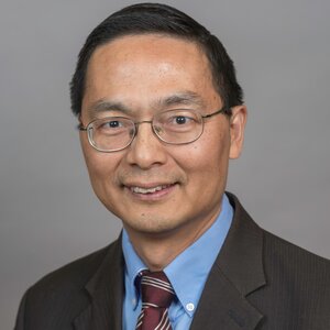 Head shot of Professor Huimin Zhao in a dark suit jacket, blue collared shirt and dark tie