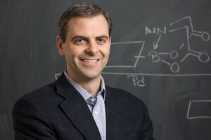Head shot of Martin Burke in a suit jacket and collared shirt in front of a blackboard with chemistry calculations