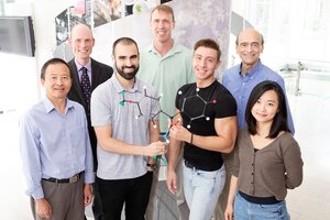 Group photo of the research team with two team members in middle front holding a molecular structure.