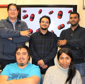 The six researchers pose together in front of a screen showing carbon molecules.