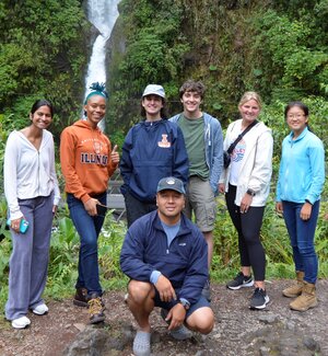 Group of study abroad students and instructor stand in front of a waterfall in Costa Rica.