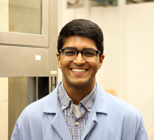 Portrait of Phil Kocheril above the shoulders in a blue lab coat in a lab setting.