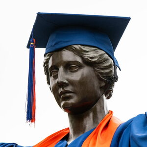 Photo of the head of the Alma Mater statue wearing a cap and gown
